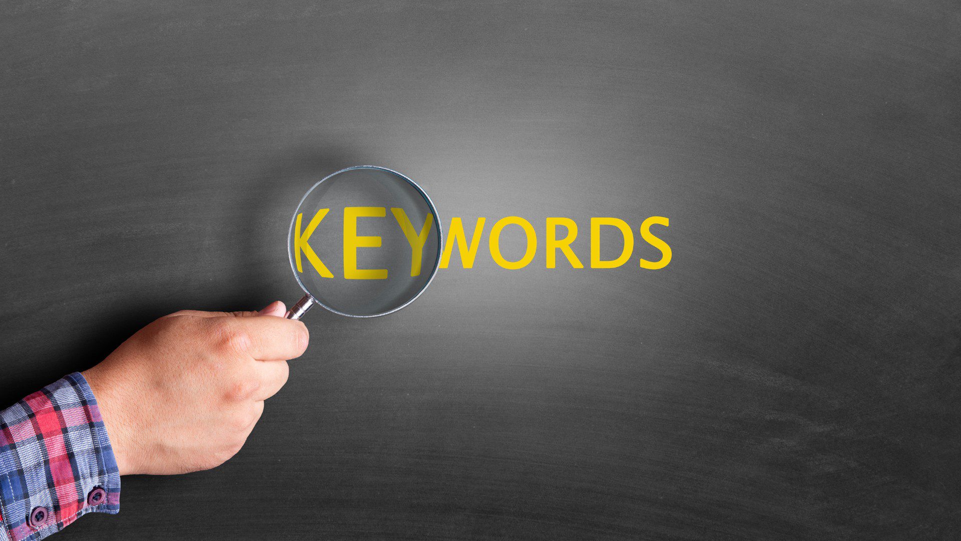 Čovek koji drži lupu koja prelazi preko reči keywords