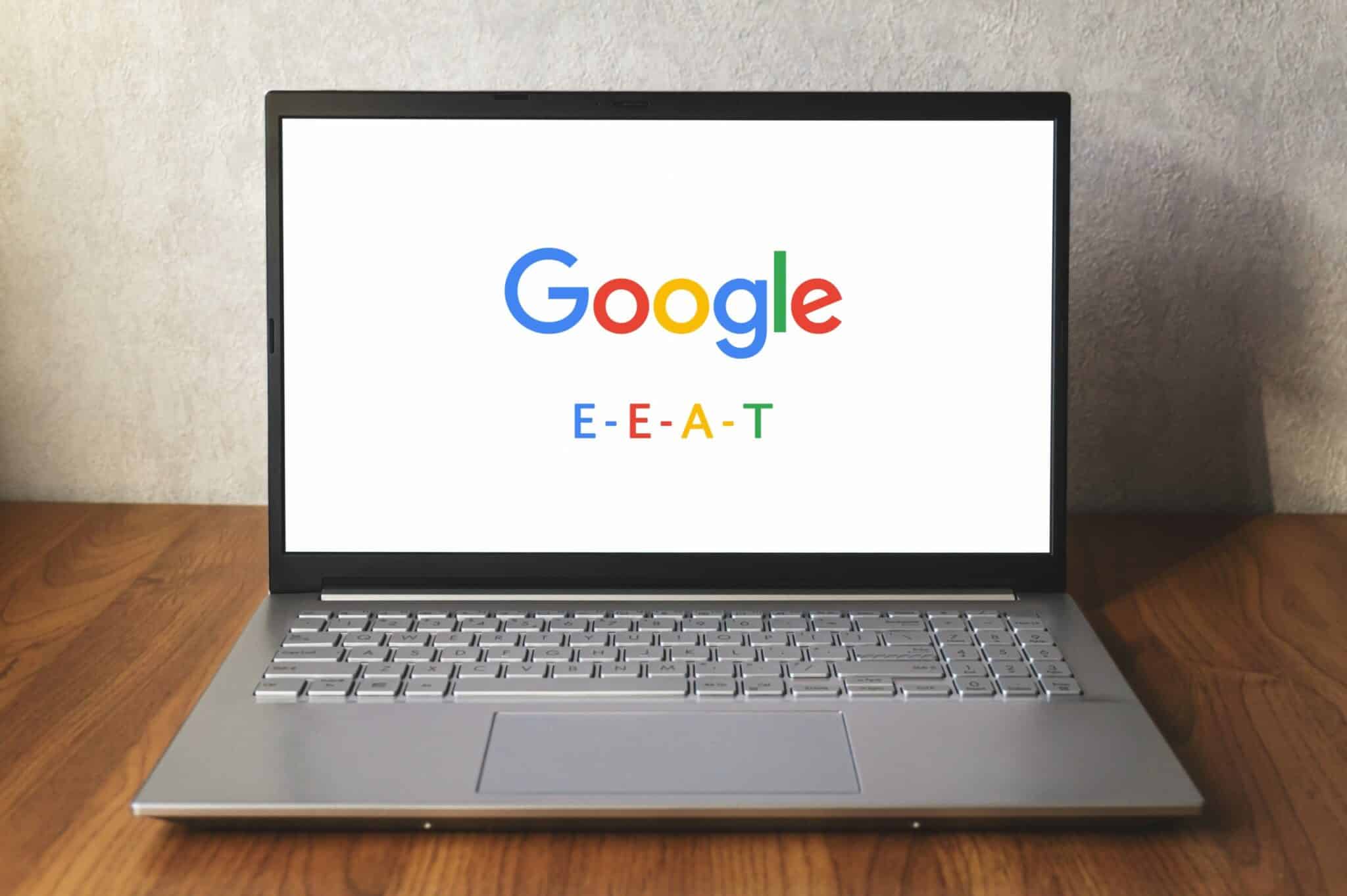 Laptop na kome je prikazan logo Gugla i ispod njega piše E-E-A-T